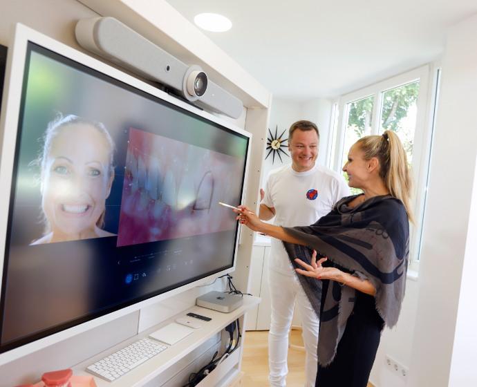Dr. Sebastian Horvath berät eine Patientin die ihre gewünschte Form der Veneers mit einem Stift auf einem Touchscreen malt.
