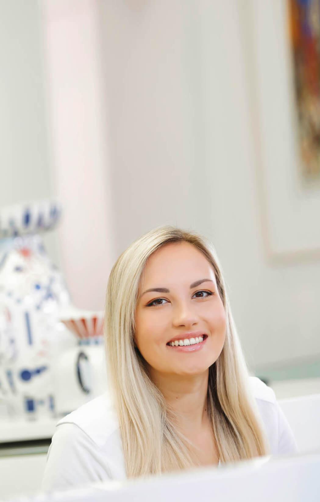 Freundliche Rezeptionistin lächelt in der Praxis Dr. Horvath