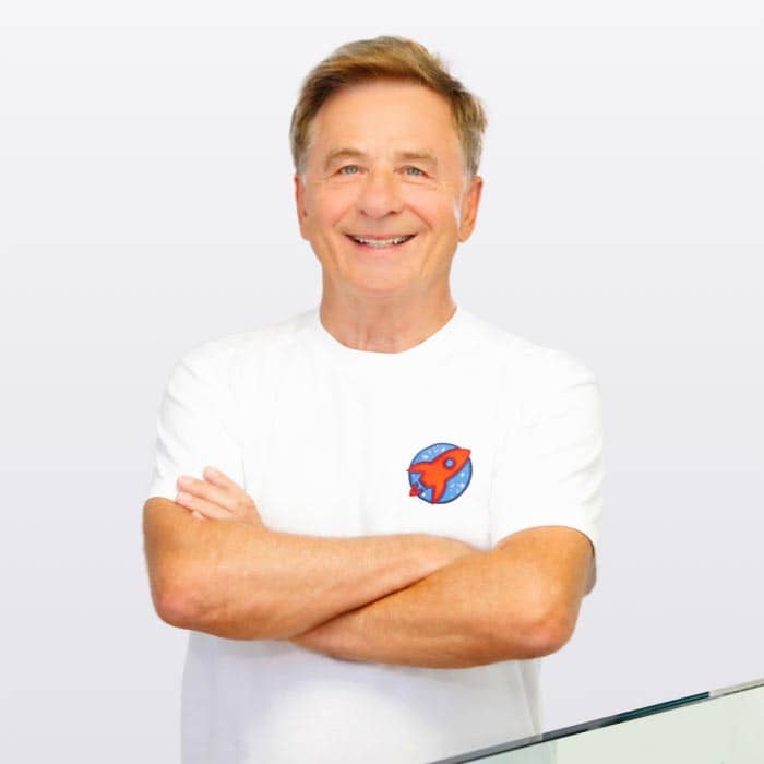 Porträt von Dr. Domonkos Horváth, einem erfahrenen Zahnarzt, der mit verschränkten Armen lächelnd in seiner Praxis steht, was Vertrauen und Professionalität ausstrahlt.