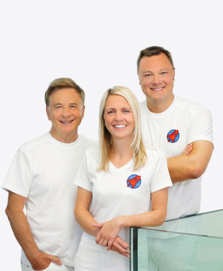 Herzlicher Empfang bei Dr. Horvath: Dieses Bild präsentiert das freundliche und professionelle Team der Zahnarztpraxis, bestehend aus Dr. Nicole Horvath, Dr. Sebastian Horvath und Dr. Domonkos Horvath, alle lächelnd in ihren Praxisuniformen mit dem Praxislogo, bereit, den Patienten die beste Zahnversorgung zu bieten.