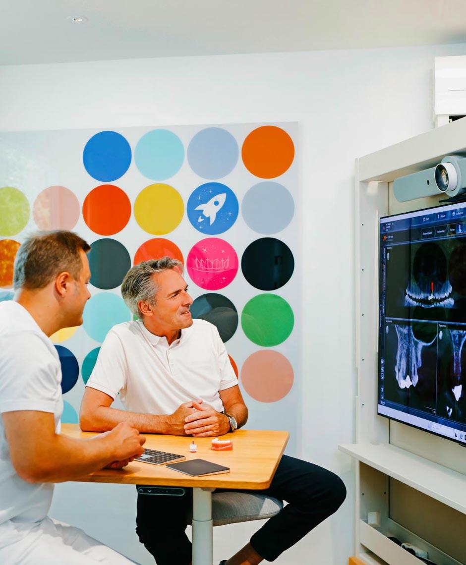 Dr. Sebastian Horvath bespricht mit einem Patienten die digitale 3D-Planung für Zahnimplantate in der Zahnarztpraxis Jestetten bei Zürich.