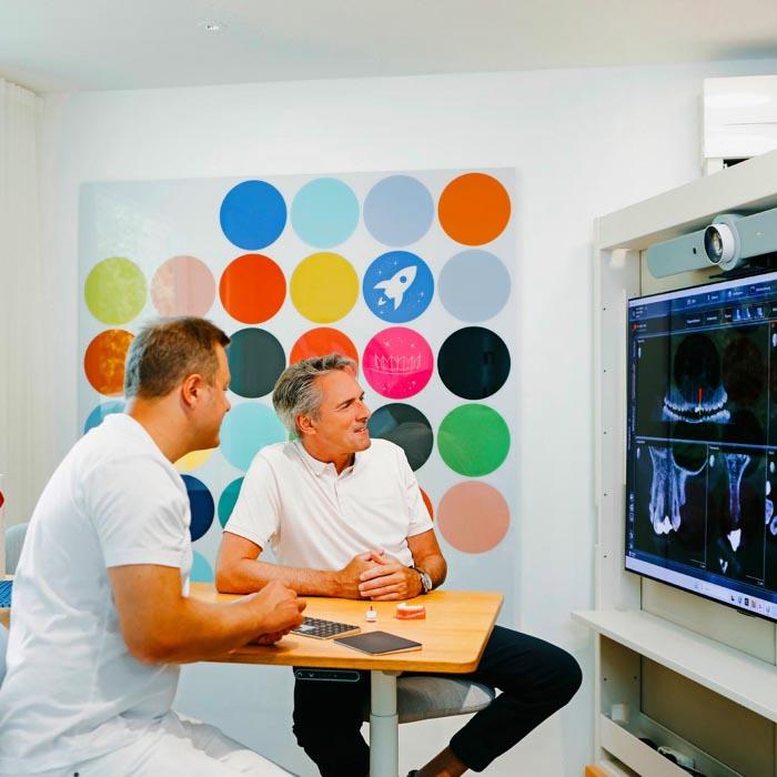 Dr. Sebastian Horvath bespricht mit einem Patienten die digitale 3D-Planung für Zahnimplantate in der Zahnarztpraxis Jestetten bei Zürich.