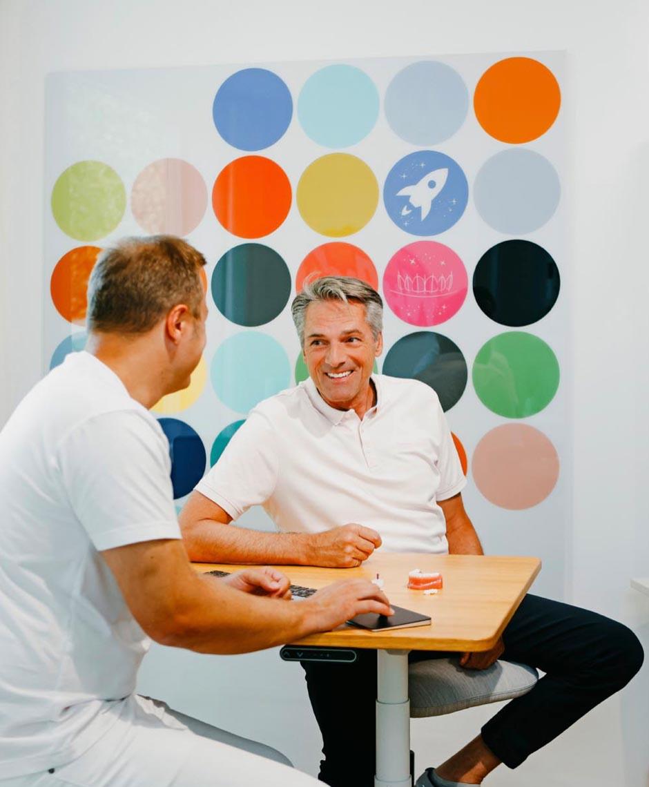 Dr. Sebastian Horvath erklärt einem Patienten die Möglichkeiten der Zahnsanierung und des Zahnersatzes in der modernen Praxis in Jestetten nahe Zürich.