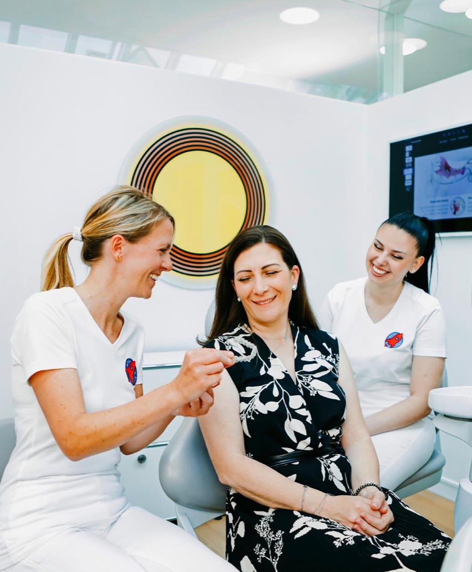 Dr. Nicole Horvath zeigt erwachsener Patientin eine Invisalign-Schiene in der Zahnarztpraxis Jestetten, Raum Zürich – ästhetische Zahnkorrekturen.