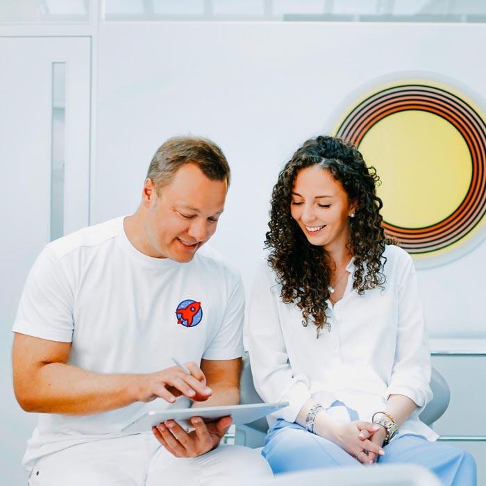 Dr. Sebastian Horvath erklärt Patientin den Invisalign-Behandlungsplan mit digitaler Technik in der Zahnarztpraxis Jestetten nahe Zürich.