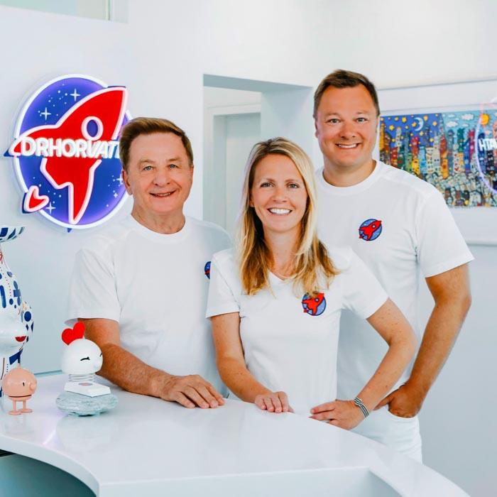 Dr. Nicole Horvath, Dr. Sebastian Horvath und Dr. Horvath senior im Empfangsbereich der Zahnarztpraxis Jestetten bei Zürich – Experten für Kieferorthopädie, Invisalign, Veneers und Zahnimplantate.