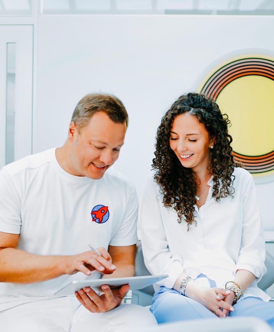 Dr. Sebastian Horvath erklärt Patientin den Invisalign-Behandlungsplan mit digitaler Technik in der Zahnarztpraxis Jestetten nahe Zürich.