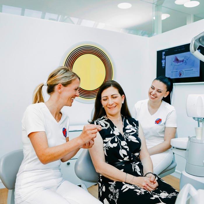 Dr. Nicole Horvath zeigt erwachsener Patientin eine Invisalign-Schiene in der Zahnarztpraxis Jestetten, Raum Zürich – ästhetische Zahnkorrekturen.