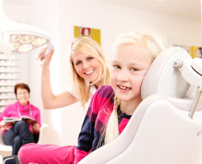 Dr. Nicole Horvath und Ihre Junge Patientin welche gerade auf dem Behandlungsstuhl sitzt lachen freundlich in die Kamera.