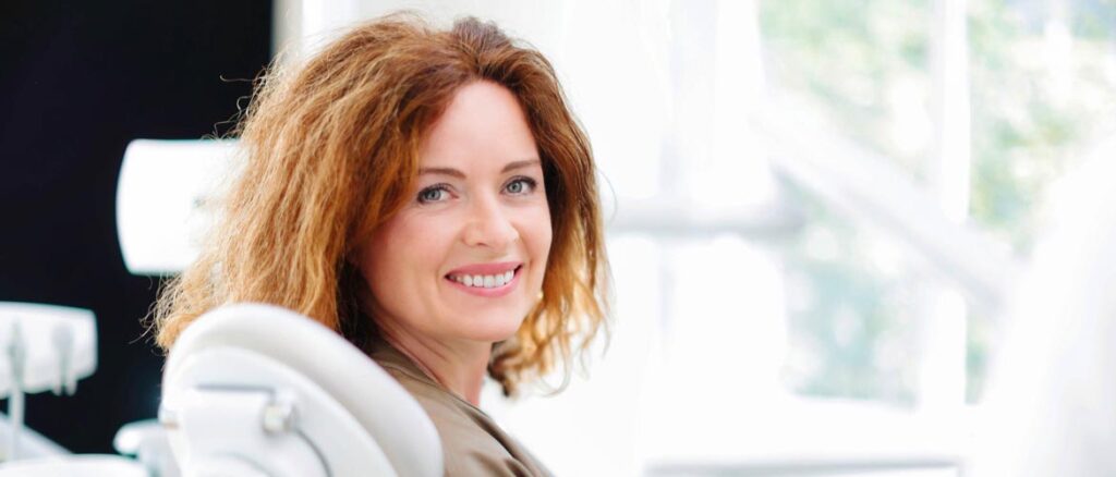 Glückliche Patientin zeigt ihr strahlendes Lächeln nach erfolgreicher kieferorthopädischer Behandlung