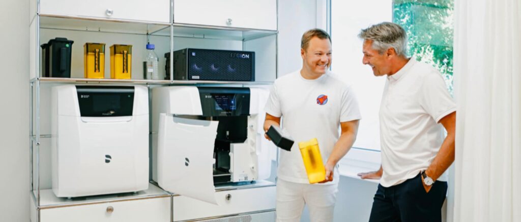 Dr. Sebastian Horvath berät einen Patienten vor dem 3D-Drucker in der Praxis Dr. Horvath in Jestetten